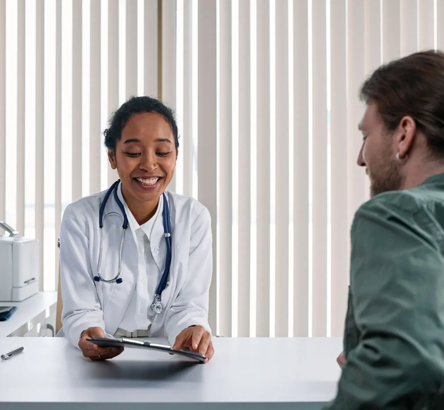 A clinician smiling at a patient while showing them a tablet